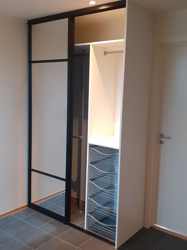 Komplett skyvedørsgarderobe bestående av skyvedører med klart speil og svarte profiler og sprosser, og garderobeinnredning tilpasset på mål