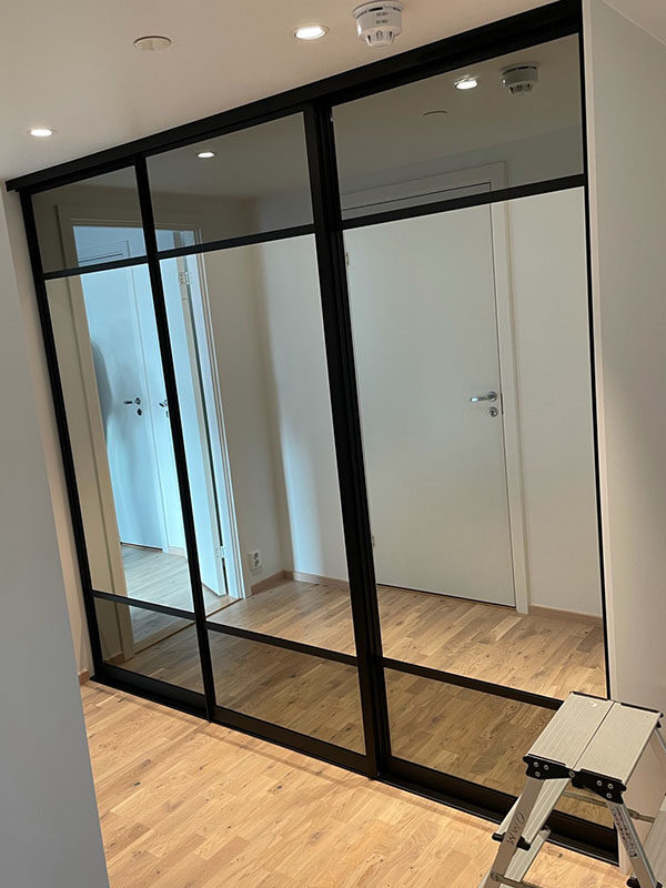 skyvedører med kombinasjoner av sotet og klart speil og sprosser som dekor på skyvedørsfrontene