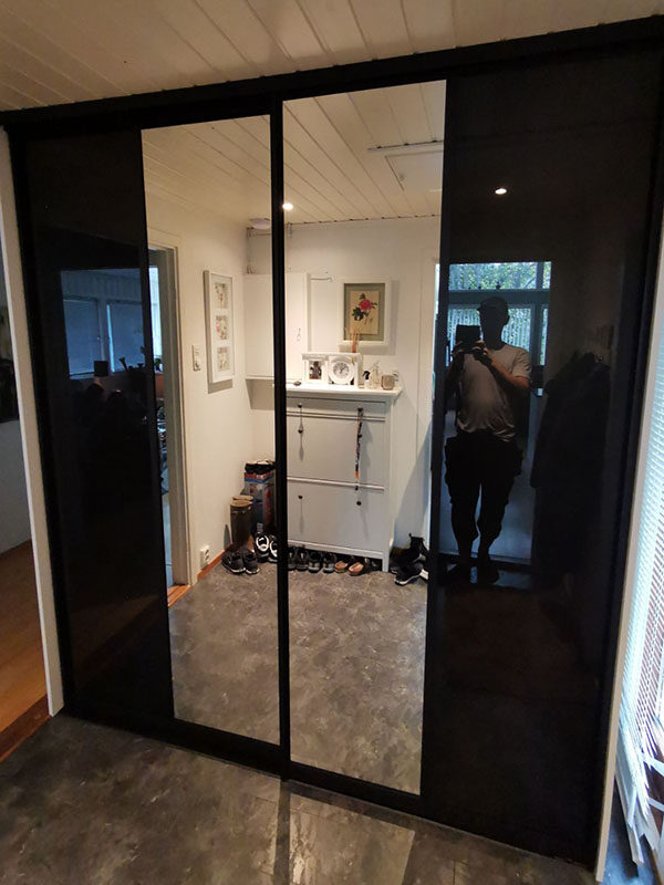 skyvedørsgarderobe i gang med skyvedører med svart glass og klart speil