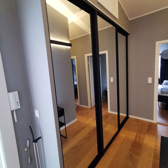skyvedørsgarderobe i gang med skyvedører med speil og svarte profiler