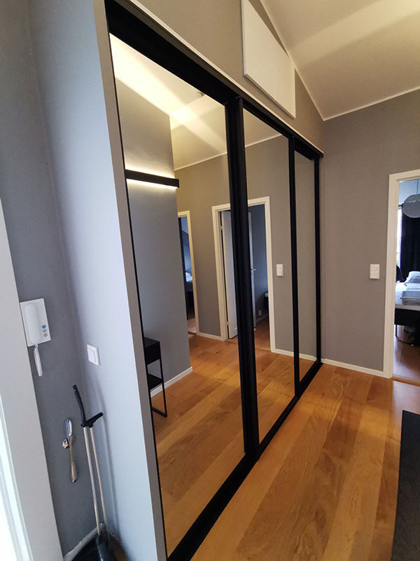 skyvedørsgarderobe i gang med skyvedører med speil og svarte profiler