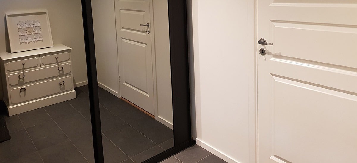 Skyvedørsgarderoben med speil helt ned til gulvet får den lille gangen til Ingeborg til å fremstå som større og mer romslig. Og plassen utnyttes maksimalt med smart innredning. Les mer på garderobemekka.no