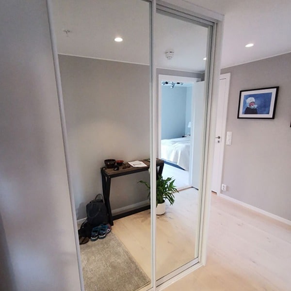 Skyvedørsgarderoben med speil helt ned til gulvet får den lille gangen til Ingeborg til å fremstå som større og mer romslig. Og plassen utnyttes maksimalt med smart innredning. Les mer på garderobemekka.no