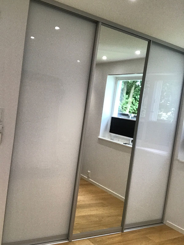 skyvedørsgarderobe på soverom med klart speil og hvitt glass, samt profiler i aluminium